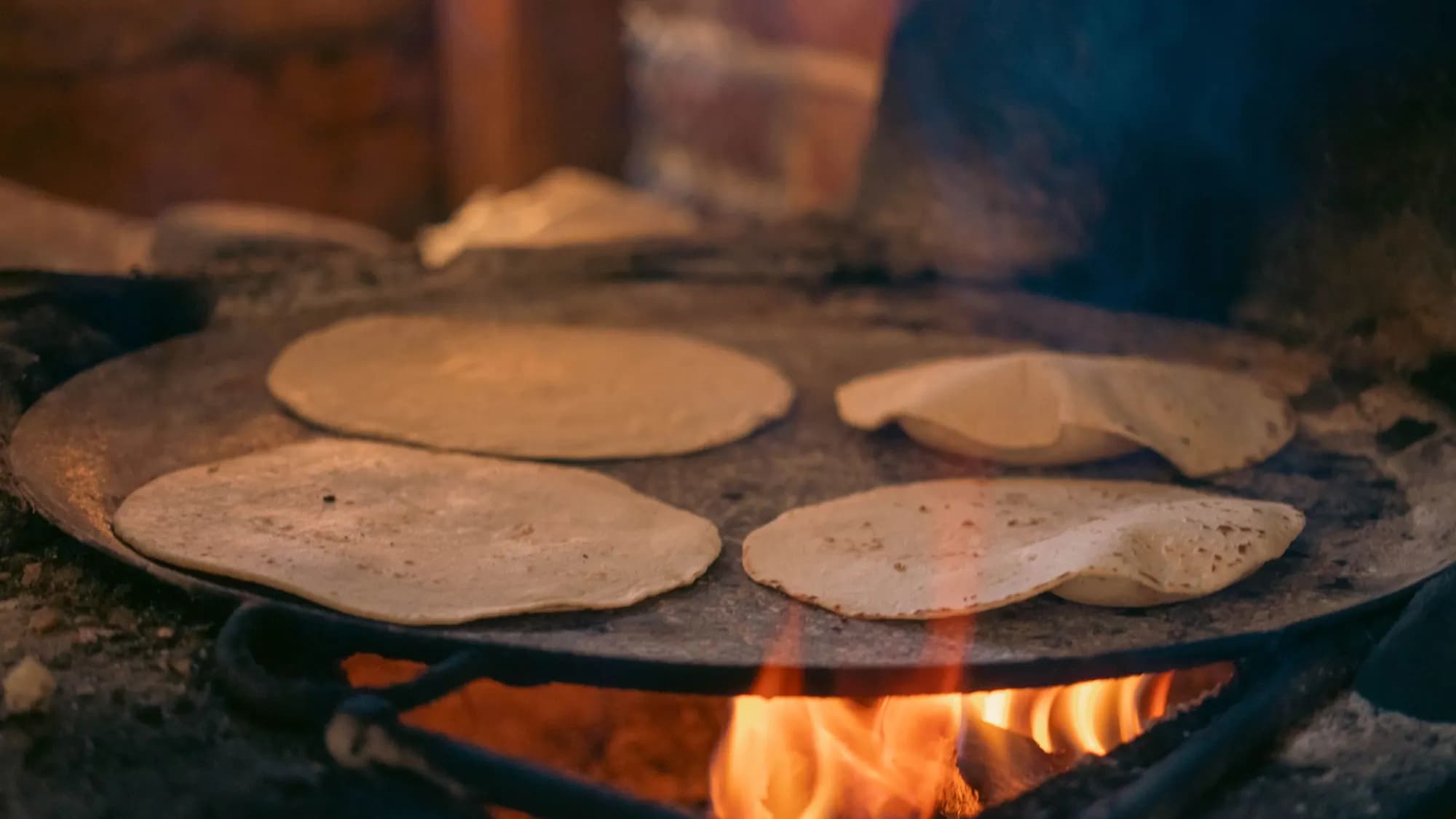 Corn tortillas cooking on a hot comal in a Mexican street kitchen