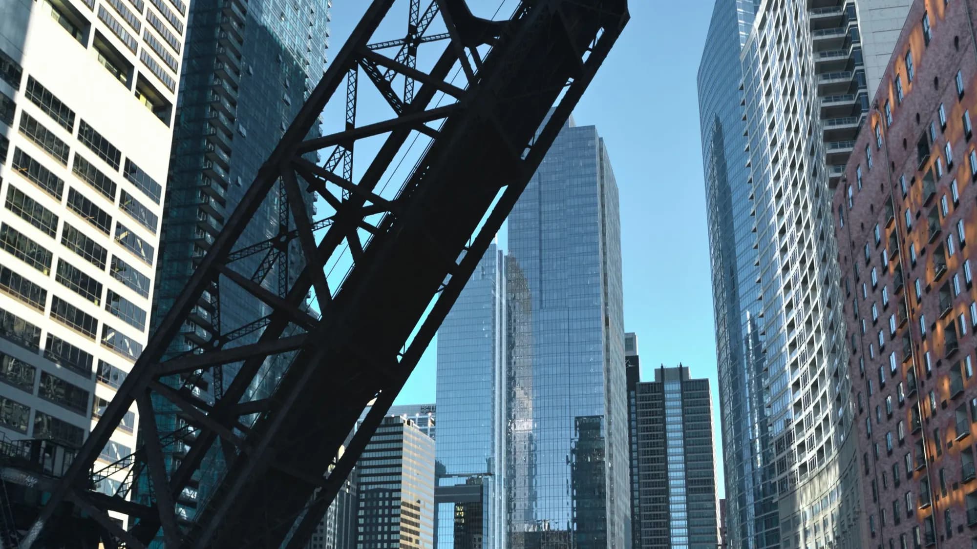 A raised steel drawbridge on the Chicago River, seen from below against the towers