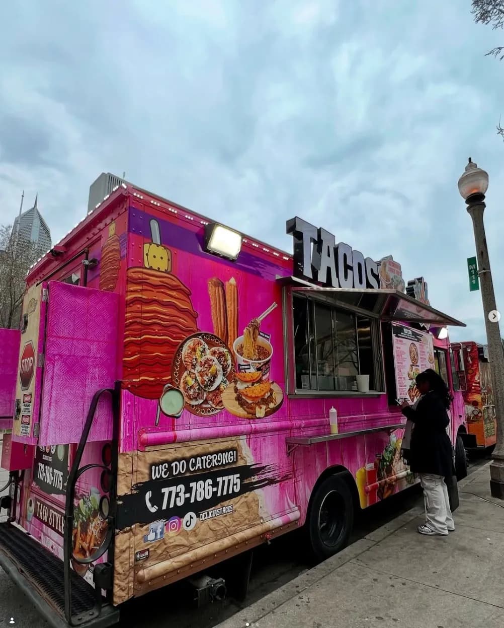 Customer ordering at the Delicias Tacos pink food truck in downtown Chicago