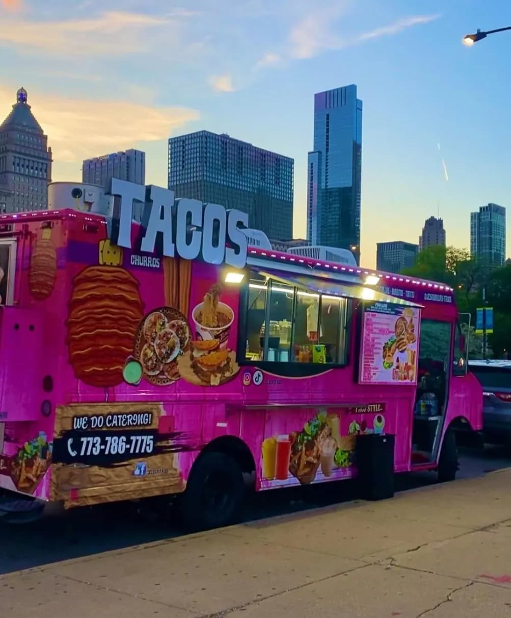 Delicias Tacos pink food truck with the Chicago skyline at sunset
